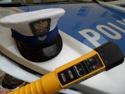 na pokrywie silnika radiowozu oznakowanego leży czapka policjanta ruchu drogowego i urządzenie do badania stanu trzeźwości kierujących.
