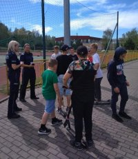 Dwie policjantki stoją przy skateparku na terenie Ośrodka Sportu i rozmawiają z grupą 8 chłopców w wieku 12-15 lat.