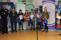 Komendant Powiatowy Policji w Policach i Burmistrz Polic stoją z nagrodzonymi uczestnikami turnieju. Dzieci trzymają dyplomy.