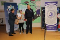 Komendant Powiatowy Policji w Policach i Burmistrz Polic stoją z nagrodzoną uczestniczką turnieju. Dziewczynka trzyma dyplom