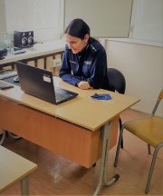 na zdjęciu w szkole, w klasie,  za biurkiem siedzi policjantka, która przez komputer rozmawia z uczniami o nienawiści.