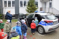 Dzieci stoją na dworze na parkingu za Komenda, oglądają radiowóz oznakowany.